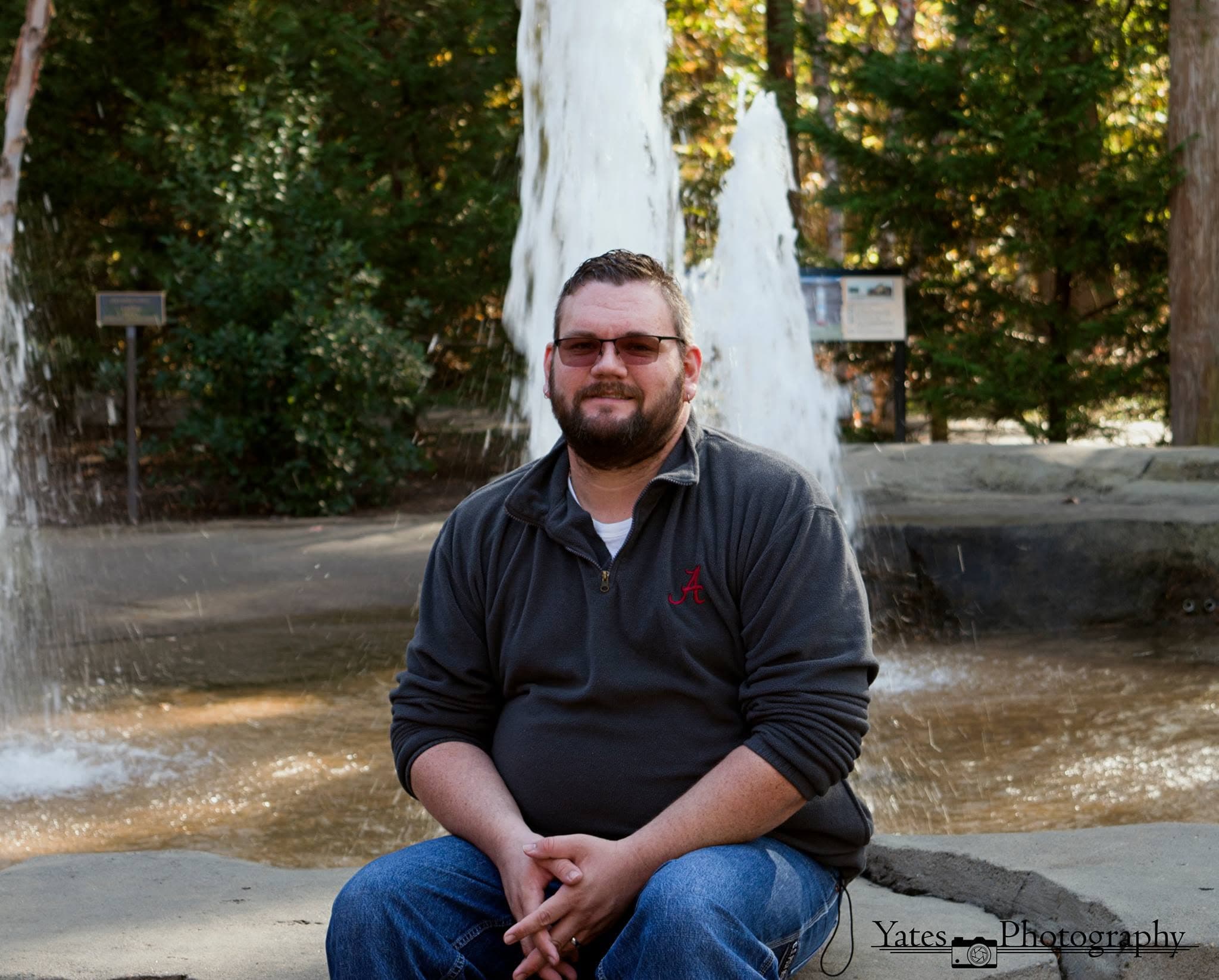 Brian Yates, founder of Yates Travel, sitting in front of a fountain